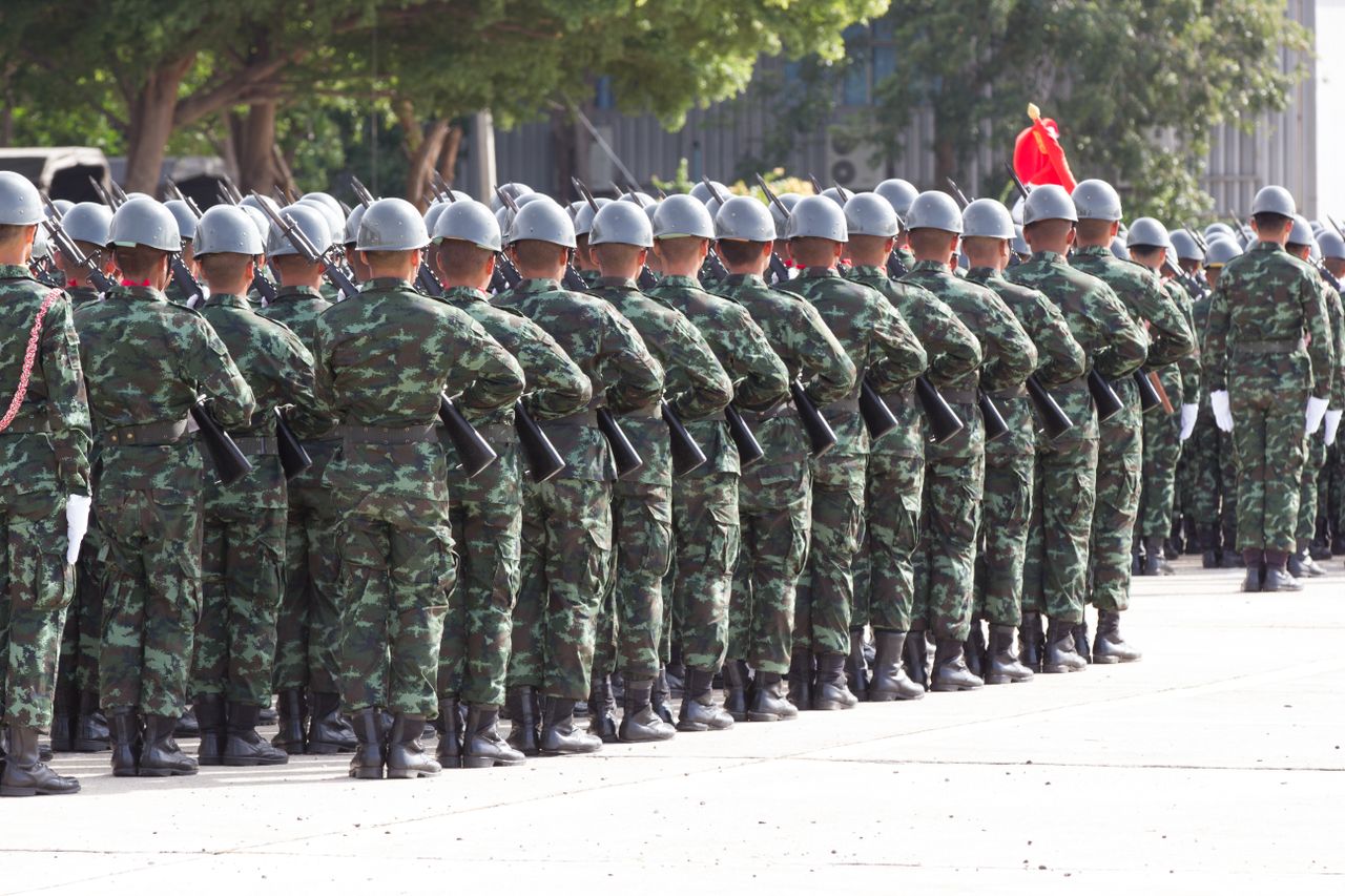 services-02 Back view unrecognizable soldiers with riffles wearing khaki uniform and hardhat lining up in rows during military ceremony