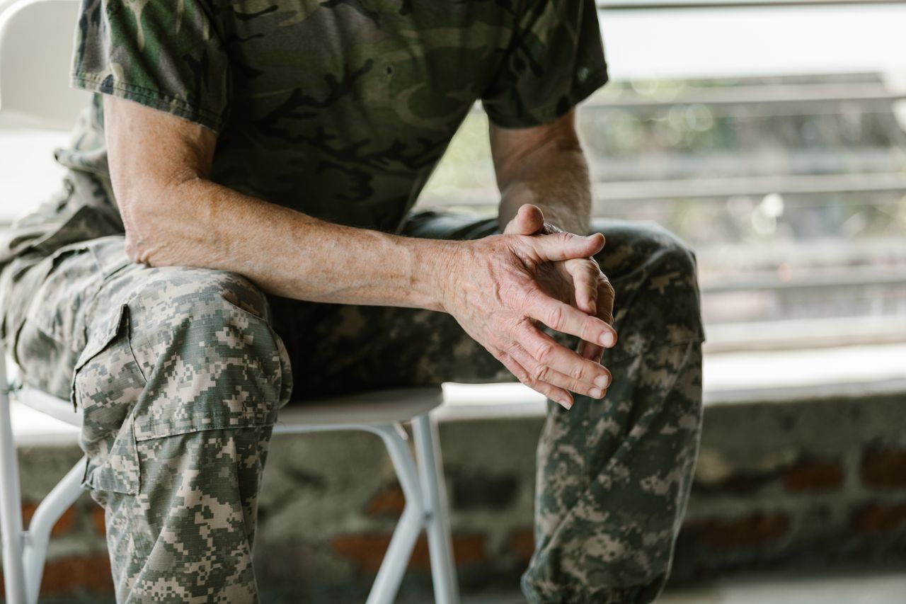 about-img Close-up of a military veteran's hands in a therapy session, emphasizing mental health support.